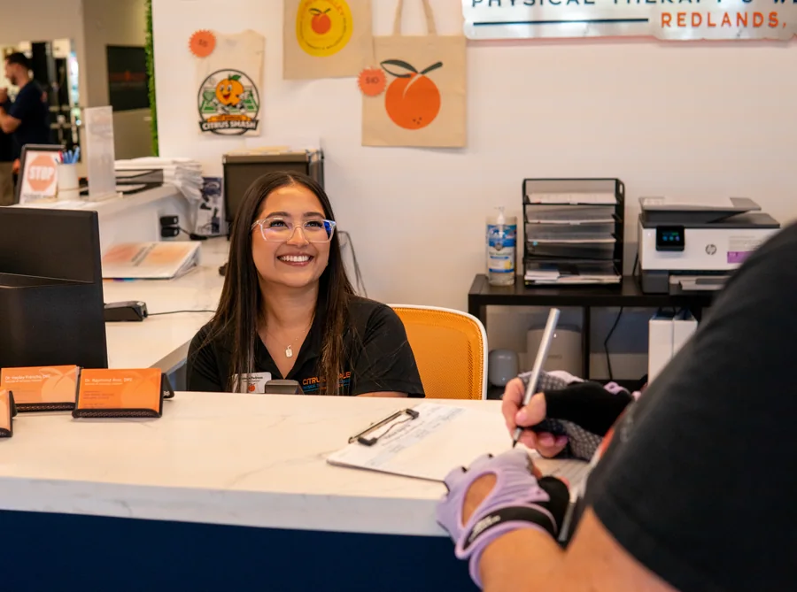Front desk team member smiling while a patient fills out paperwork at the Citrus Valley front desk